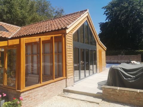 Oak-framed garden room with full-height glazing beside a swimming pool